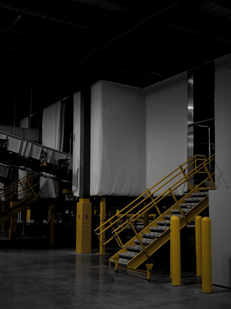 White acoustic curtain system above a conveyor access stair in a warehouse facility